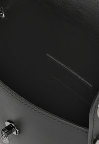 Borsa a mano in pelle nera con texture liscia, design arrotondato e dettaglio di chiusura a lucchetto argentato. Interno scuro e senza decorazioni.