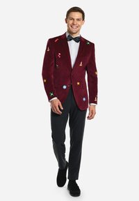 Burgundy velvet suit jacket with colorful holiday-themed embroidery. Paired with gray trousers and a white shirt, worn with a black bow tie.