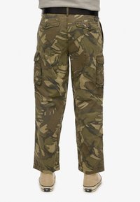 Cargo bukser i et grønt og brunt camouflage mønster; har sidelommer, knap-lukket baglommer og en afslappet pasform.