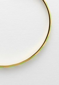 Collana in metallo dorato con forma rotonda e liscia. Presenta segmenti alternati di oro puro e accenti verdi, creando un motivo testurizzato.