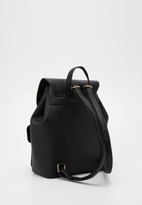 Czarny skórzany plecak o usztywnionym kształcie, z zaokrąglonym wierzchem, dwoma uchwytami do przenoszenia i złotymi akcentami metalowymi. Gładka tekstura.