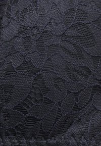Tecido de renda escura com um padrão floral e muitos detalhes, trama texturizada e bordas recortadas. Superfície suave com um brilho subtil.