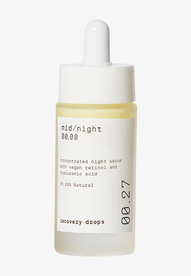 Konsentrert nattserum i en klar glassflaske med hvitt dråpehette. Lysegul væske, merket med svart tekst og et minimalistisk design.