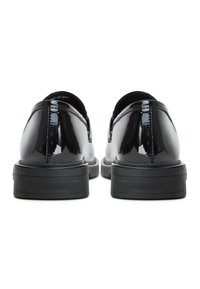 Black patent leather shoes with rounded toes, low heels, and smooth, glossy texture. Features visible stitching and a textured sole.