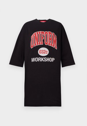 Czarna, oversize koszulka wykonana z bawełny, z wyraźnym czerwonym i białym napisem: "UNIFORM 032c WORKSHOP" na przodzie. Okrągły dekolt, krótkie rękawy.