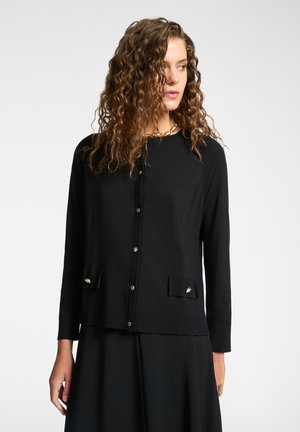 Zwarte cardigan gemaakt van zachte stof, met een ronde halslijn, knoopsluiting en decoratieve voorzakken met accenten.