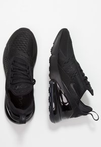Ett par svarta Nike Air Max 270 sneakers med nätovandel och synlig luftkuddning på en vit bakgrund.