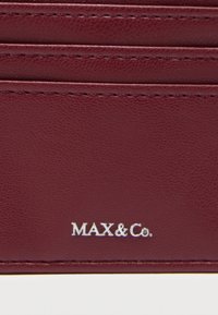 Bordeauxrood lederen kaarthouder met geperst logo "MAX&Co." en zichtbare stikseldetails; slank ontwerp met meerdere vakken voor kaarten.