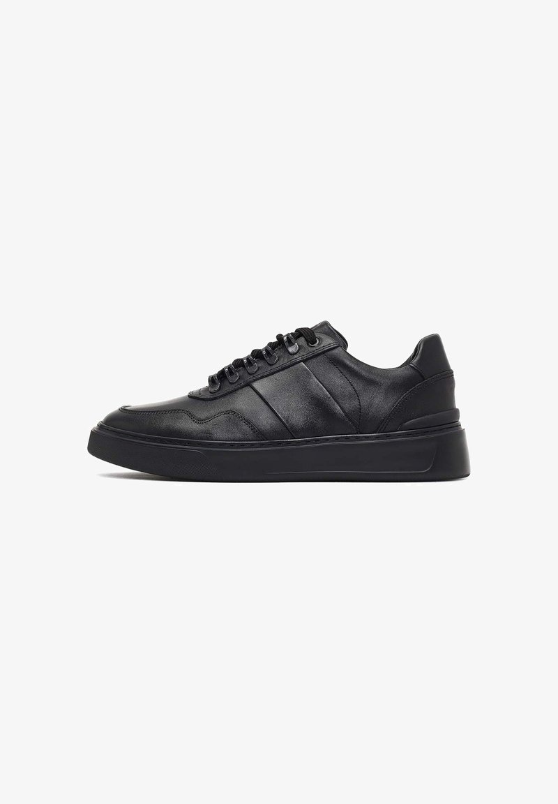 Black leather sneakers with a smooth finish, round toe, textured side stripes, black laces, and a thick black rubber sole.