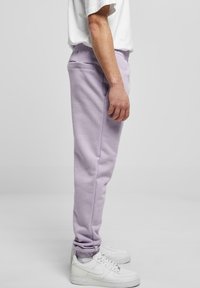 Hellblaue Sweatpants mit einem elastischen Bund und gerippten Knöcheln, die eine Seitentasche haben. Kombiniert mit weißen Turnschuhen.