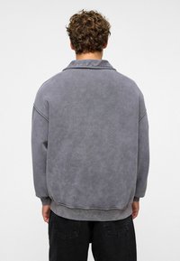 Grijze sweatshirt met een ontspannen pasvorm, kraag en verlaagde schouders; zachte, gestructureerde stof; ribbelboorden en onderrand; minimalistisch ontwerp.