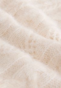 Teksturirana kremasta tkanina z mehkim, puhastim videzom, z nežnim vzorcem in lahkotno, zračno kakovostjo.