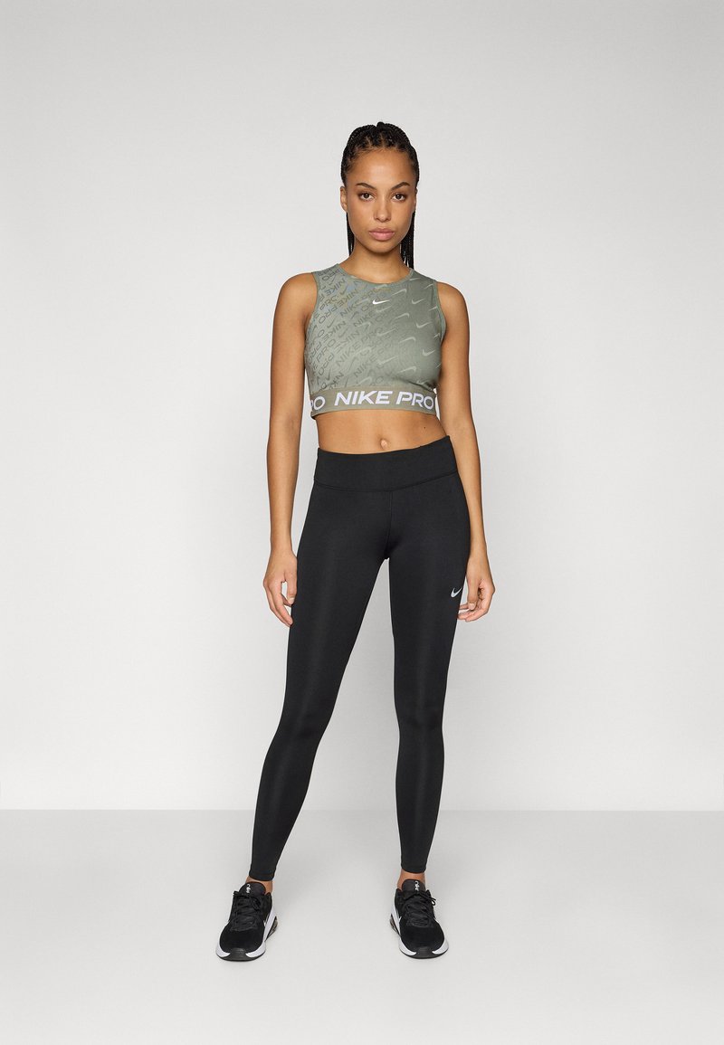 Top corto sin mangas verde con un patrón texturizado y banda Nike Pro blanca, combinado con leggings negros que tienen un pequeño logotipo de Nike.