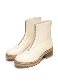 Botas de tobillo de piel beige con dobles cremalleras, parte superior texturizada y una suela de goma gruesa y con relieves, con un tacón de madera.