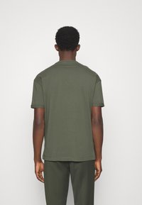 Mørkegrønt bomulds T-shirt med afslappet pasform, korte ærmer og rund halsudskæring. Har en glat tekstur og et enkelt design.