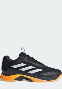 Černá sportovní bota se syntetickým svrškem, stříbrnými pruhy, oranžovou podrážkou pro lepší trakci a texturovanými černými tkaničkami pro bezpečné upevnění.