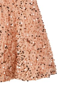 Gorący różowy materiał z cekinami, z okrągłymi i księżycowymi cekinami na brzoskwiniowym tle, tworzący teksturowaną, połyskującą powierzchnię.