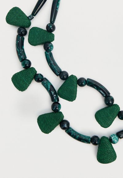 Κολιέ με εναλλασσόμενα σκούρα πράσινα υφασμένα τριγωνικά χάντρες, λείες στρογγυλές χάντρες και μαρμαρωτές καμπυλωτές σωληνωτές χάντρες σε λευκό φόντο.