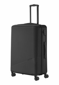 Valise rigide noire avec une surface texturée et striée, poignée extensible, quatre roulettes pivotantes et une poignée sur le côté.