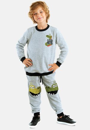 Grå bomulds sweatshirts med sort kant, der har et grønt krokodillemotiv og teksten "GOOD MOOD". Grå joggers med krokodilleansigt lommer.