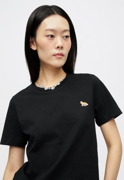 Μαύρη βαμβακερή μπλούζα με στρογγυλή λαιμόκοψη, με μικρή, πολύχρωμη κεντημένη φιγούρα ζώου στην αριστερή πλευρά του στήθους. Κοντά μανίκια.