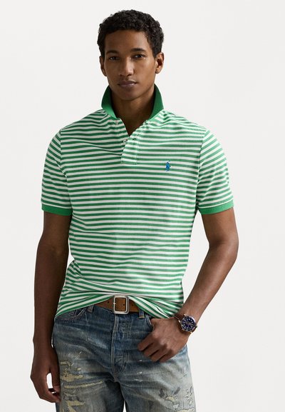 Polo verde și alb cu dungi, având un guler verde, accentuat de un mic logo albastru. Asortat cu jeans din denim uzat și o curea maro.