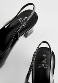 Musta patentoitu slingback-korkokenkä nelikulmaisella paksulla korolla. Varustettu pehmeällä pohjalla ja brändäyksellä sisäpohjassa. Koko 6½/40.