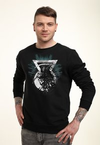 Černá mikina s grafickým potiskem kosterní postavy se srpem, obklopené netopýry a abstraktními zelenými štěpanci; froté textil.
