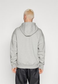 Sudadera con capucha gris de corte relajado, con capucha ajustable, puños y dobladillo de canalé, hecha de una tela suave y texturizada.