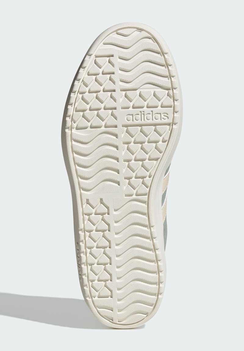 Sole of a sneaker in off-white rubber, featuring a textured, wave pattern and three horizontal stripes in a light gray color.