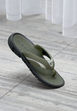 Chancla verde con suela negra, acentos blancos y correas texturizadas. Diseñada con un separador para los dedos y una plantilla acolchada.