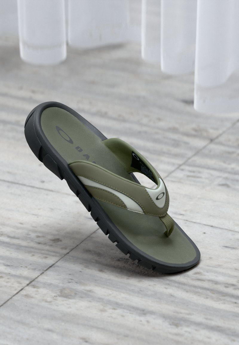 Chancla verde con suela negra, acentos blancos y correas texturizadas. Diseñada con un separador para los dedos y una plantilla acolchada.
