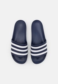 Marineblå glidesandaler med tre hvite horisontale striper, laget av glatt syntetisk materiale, med flat design og åpen tå.