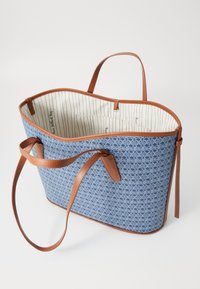 Blue patterned tote bag with brown leather accents and straps. Interior features stripes and a pocket. Open-top design for easy access.