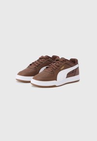 Καφέ συνθετικά αθλητικά παπούτσια με λευκές λεπτομέρειες και υφή στην επιφάνεια. Κλασικός σχεδιασμός με κορδόνια, ελαστική σόλα και διάτρητη μύτη για αναπνοή.