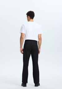 Czarne, dopasowane spodnie z zamkami bocznymi, zestawione z gładkim, białym T-shirtem. Charakteryzują się gładką teksturą materiału i minimalistycznym designem.