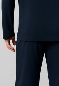 Maglia a maniche lunghe color navy e pantaloni abbinati in un tessuto morbido e liscio. Presenta un orlo dritto e semplici dettagli di cucitura.