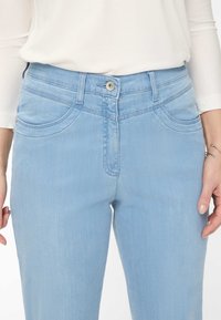 Lysblå denimjeans med slim fit, udstyret med forlommer, synlige syninger og en knaplukning i taljen.