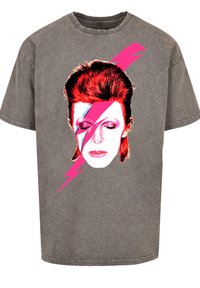 Gray oversized t-shirt made of cotton with a graphic of a face featuring red hair and a pink lightning bolt across the eye.