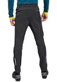 Schwarze Wanderhosen mit einem taillierten Design, aus flexiblem Material hergestellt. Verfügt über Reißverschlüsse an den Knöcheln und reflektierende Akzente an den Seiten.