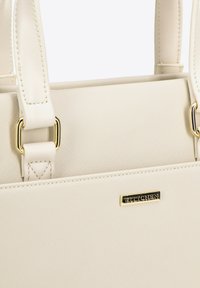Bolso de textura cremosa con doble asa para el hombro, acentos de hardware dorado y una placa de logo prominente en la parte frontal. Acabado suave y forma estructurada.