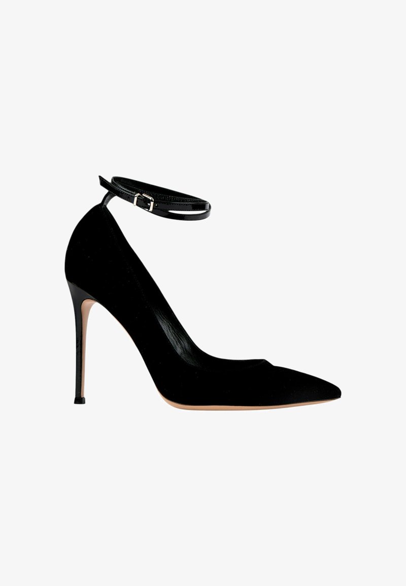Escarpin noir à talon haut avec bout pointu et fine bride de cheville avec boucle sur fond blanc.