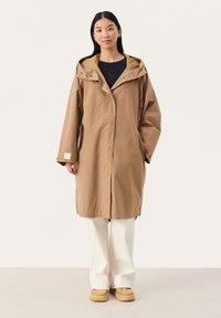 Hnědý voděodolný trench coat s kapucí, s uvolněným střihem, patentkami, bočními kapsami a hladkým, matným povrchem.