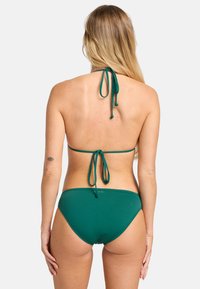 Dvojdielne zelené bikini so zaväzovaním na krku a stredne vysokými nohavičkami, vyrobené z hladkého a elastického materiálu.