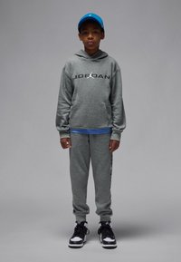 Hall hallipluus "JORDAN" logoga, sobivad spetsiaalsed dressipüksid ja musta-valge kombinatsiooniga tossud. Sinine nokamüts. Sile tekstuur, vabaaja sportlik stiil.