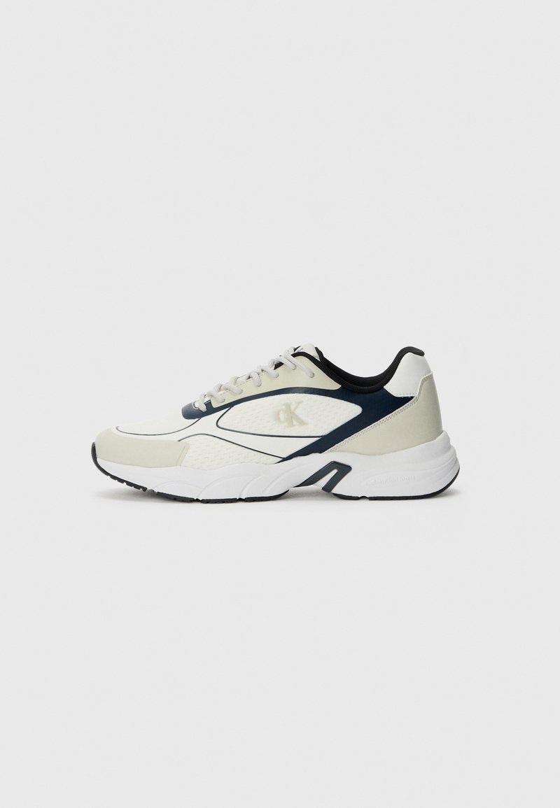 Scarpa sportiva in crema e blu navy, con tomaia in mesh, suola imbottita e accenti a contrasto. Logo visibile sul lato.