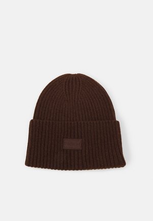 Brązowa dzianinowa czapka typu beanie z prążkowanym wzorem, z podwiniętym mankietem i małą prostokątną naszywką z logo na środku przodu.