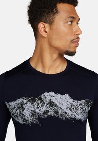 Svart långärmad tröja med en vit berggrafik över bröstet, rund hals och strukturerad tyg för komfort.