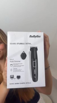 Osoba trzyma pudełko bezprzewodowego wielofunkcyjnego trymera BaByliss 6 w 1 do brody, zarostu i precyzyjnej pielęgnacji z ostrzami ze stali nierdzewnej.