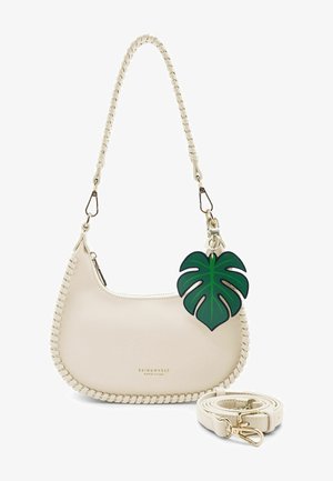 Sac à main en cuir crème en forme de croissant avec surpiqûre, bandoulière amovible et breloque feuille de monstera verte attachée à la poignée.